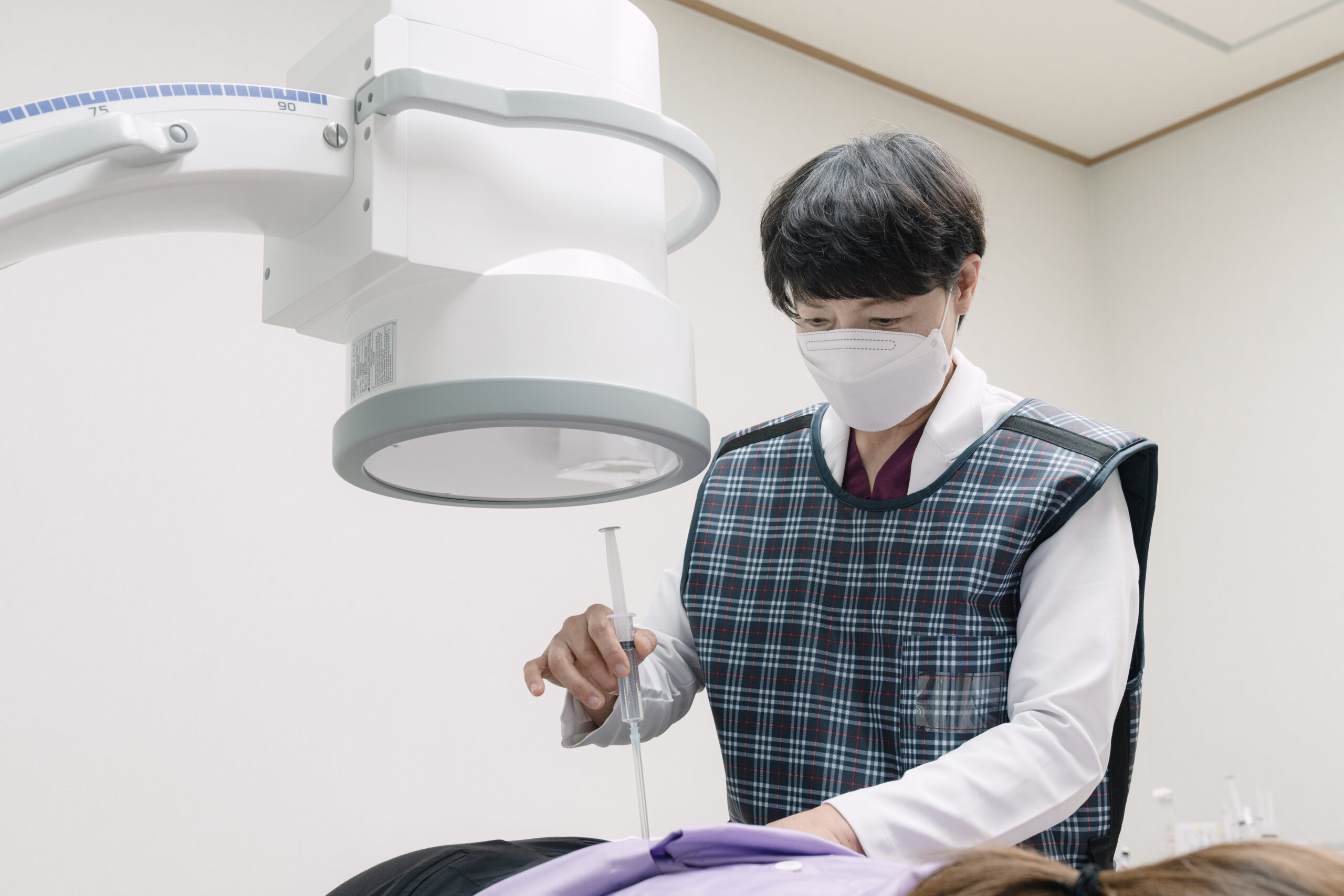 의료진이 영상 장비 아래에서 환자에게 주사 치료를 시행하는 모습